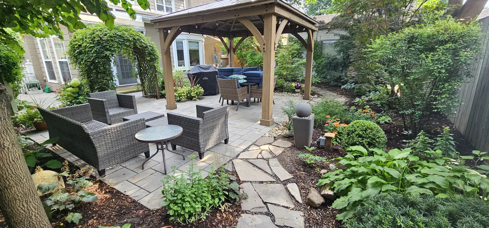 Timber pergola with patio furniture & lush garden beds