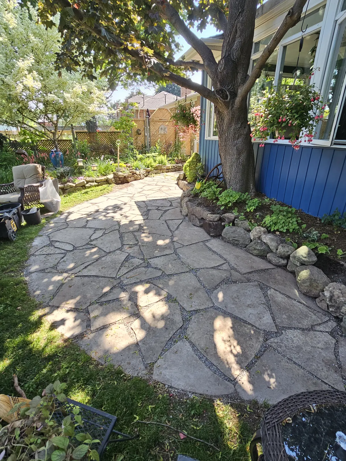 Flagstone patio with natural stone retaining wall under mature tree