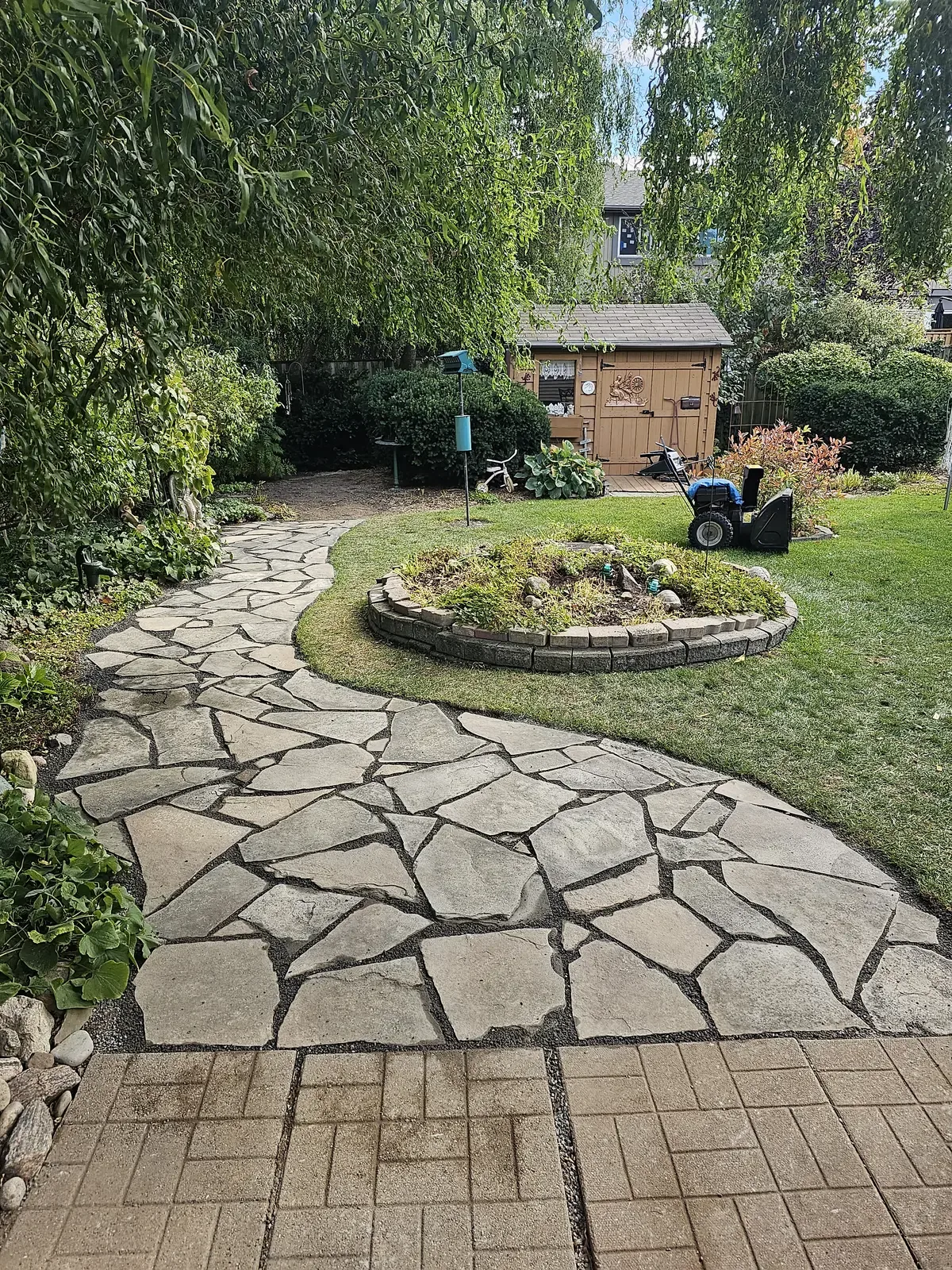 Flagstone patio with circular stone fire pit & garden border