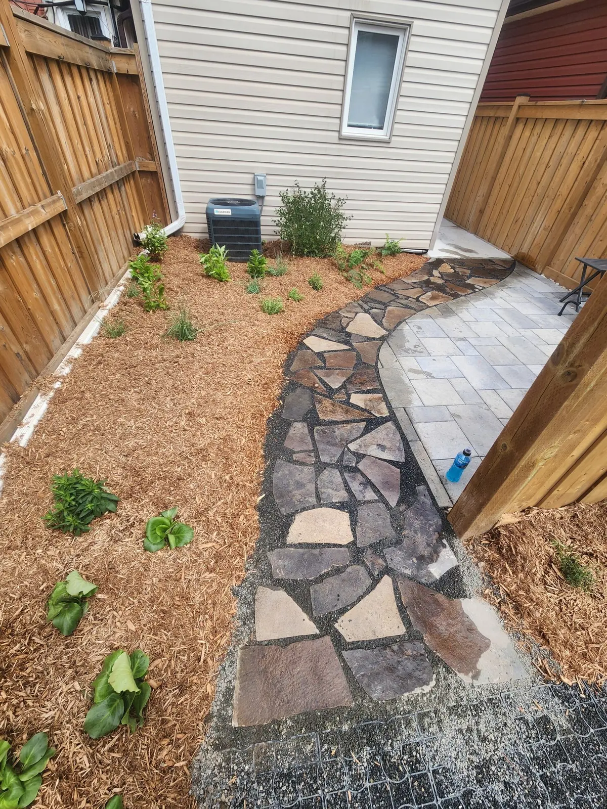 Flagstone walkway transitioning to paver patio with new plantings