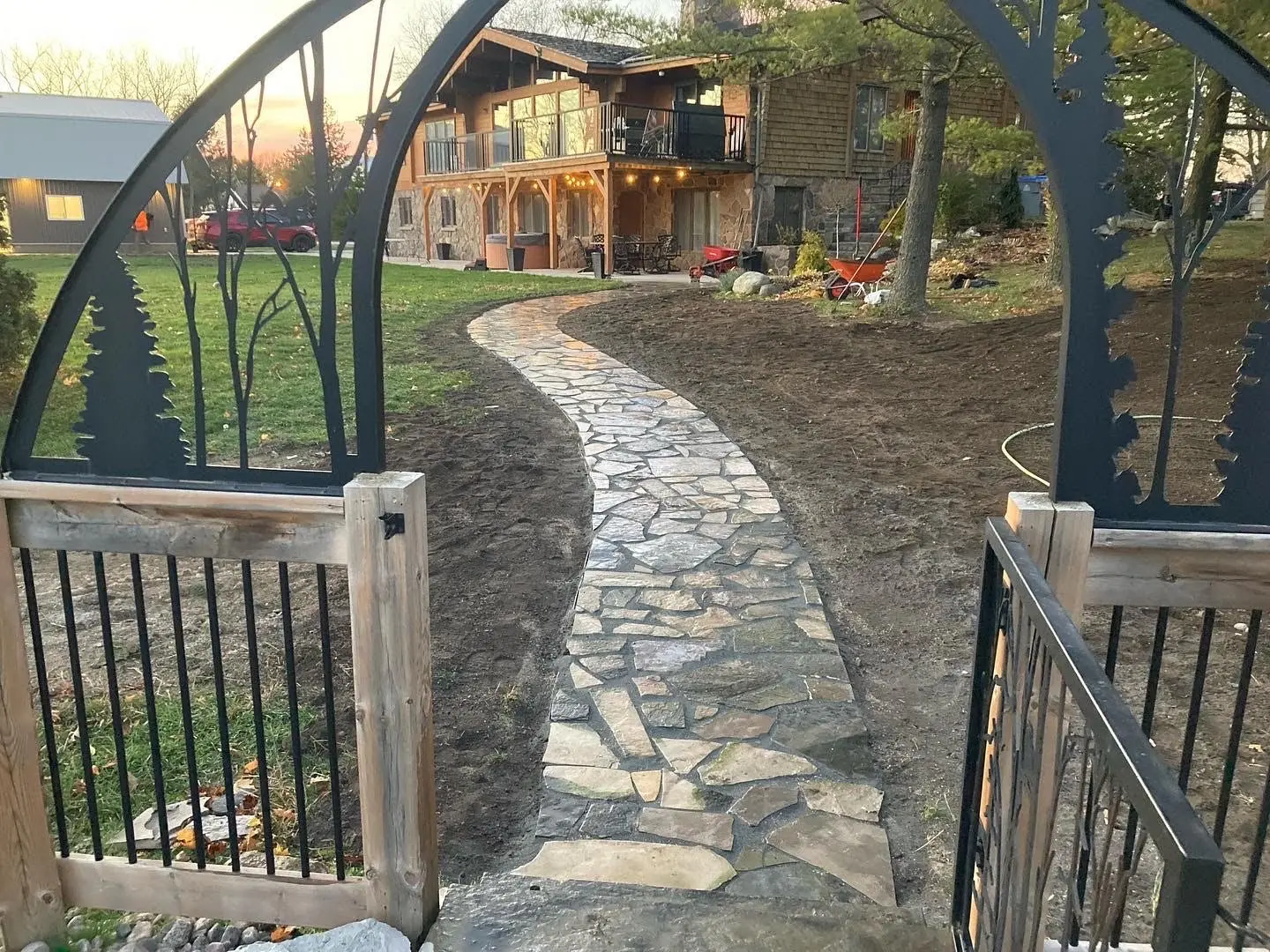 Winding flagstone walkway through decorative iron gate at dusk