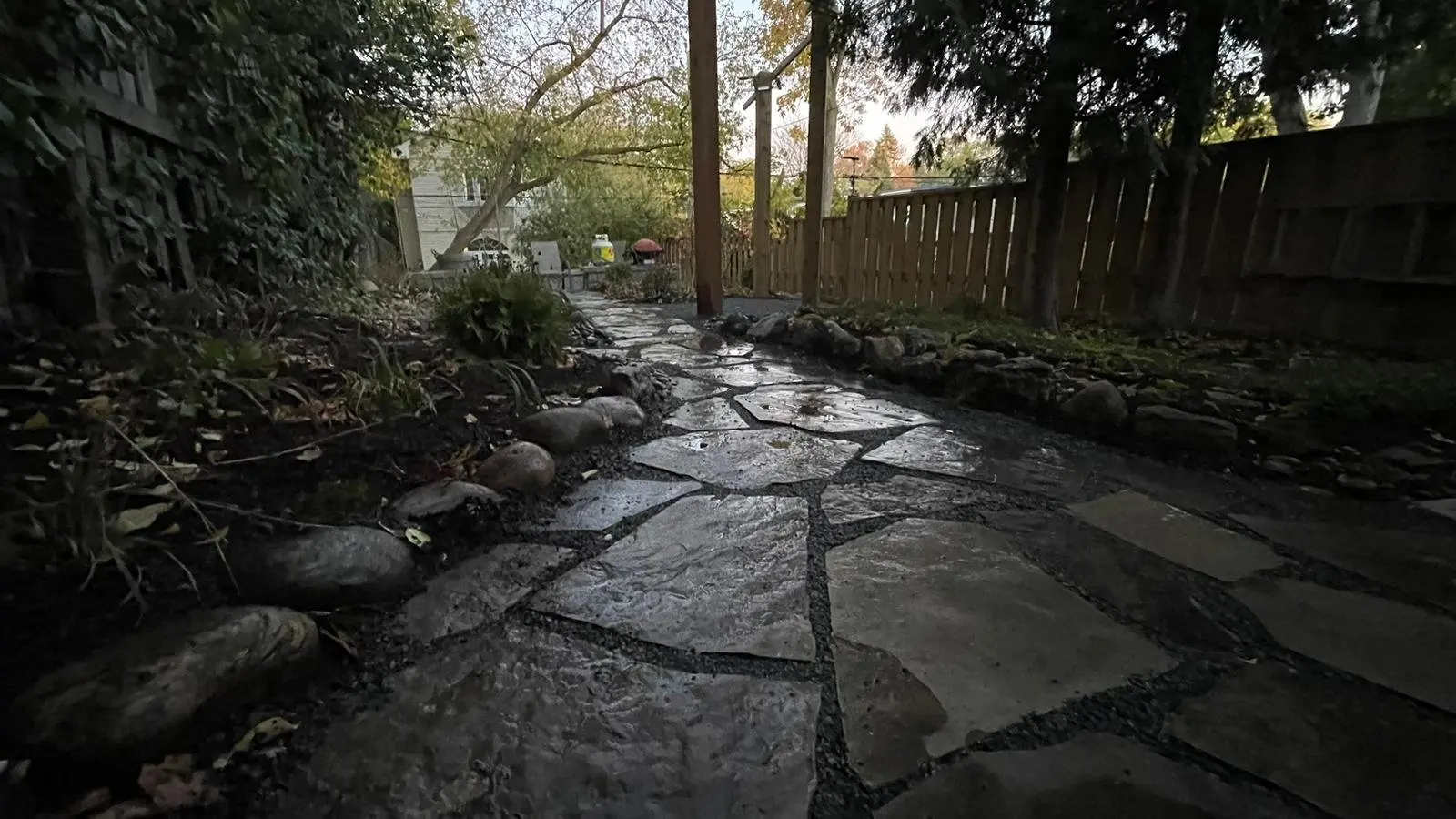 Wet flagstone pathway with river rock border in fall