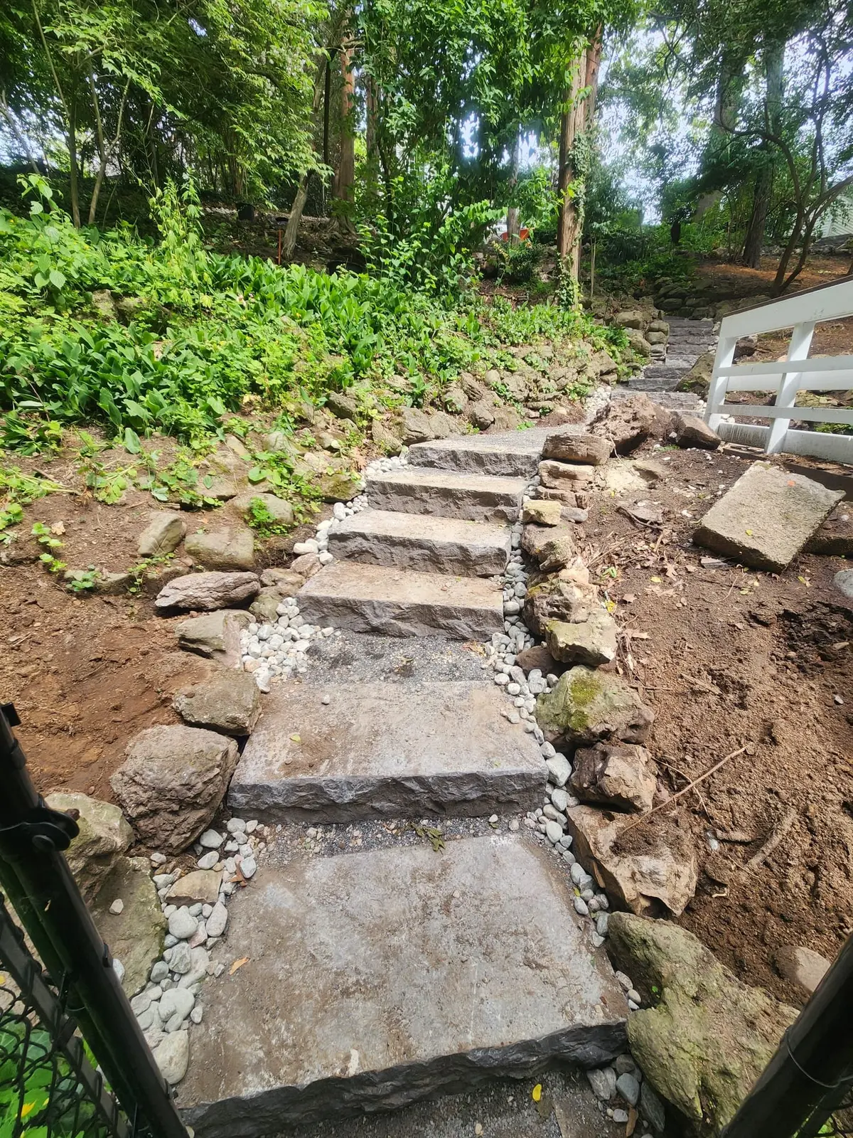 Natural stone slab steps with river rock edging through slope