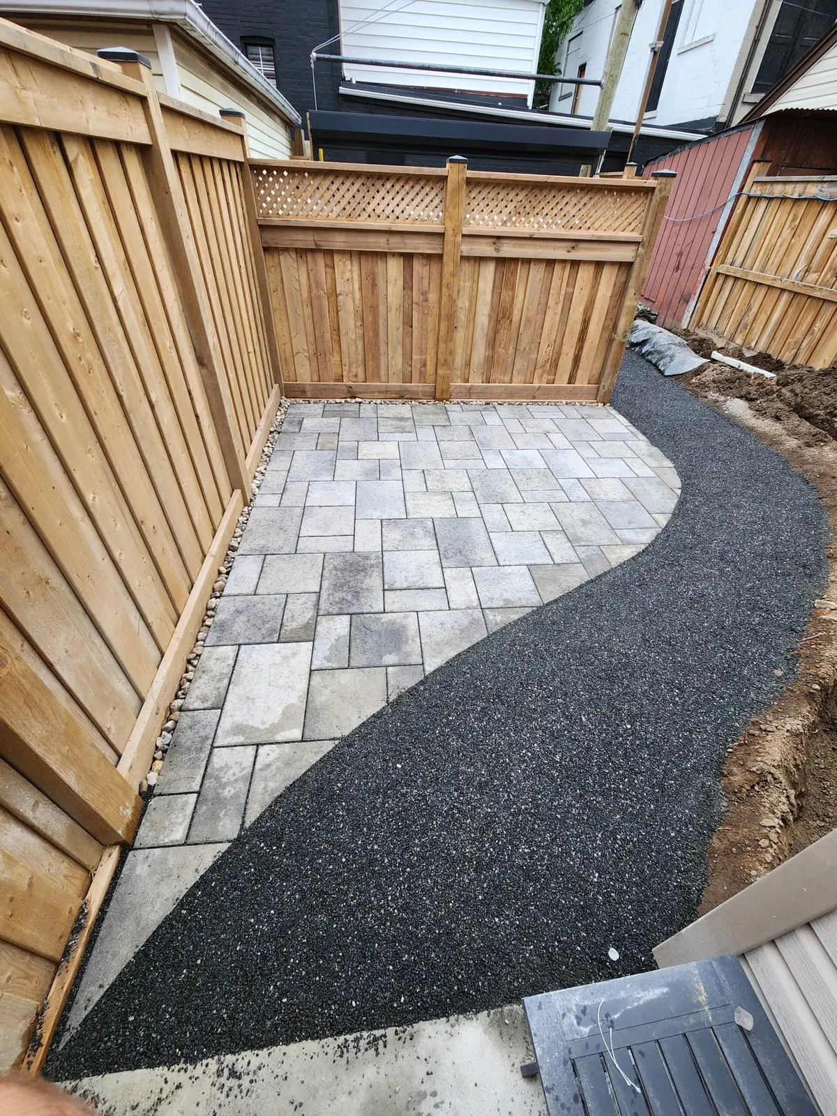 Curved paver pad with gravel path in backyard