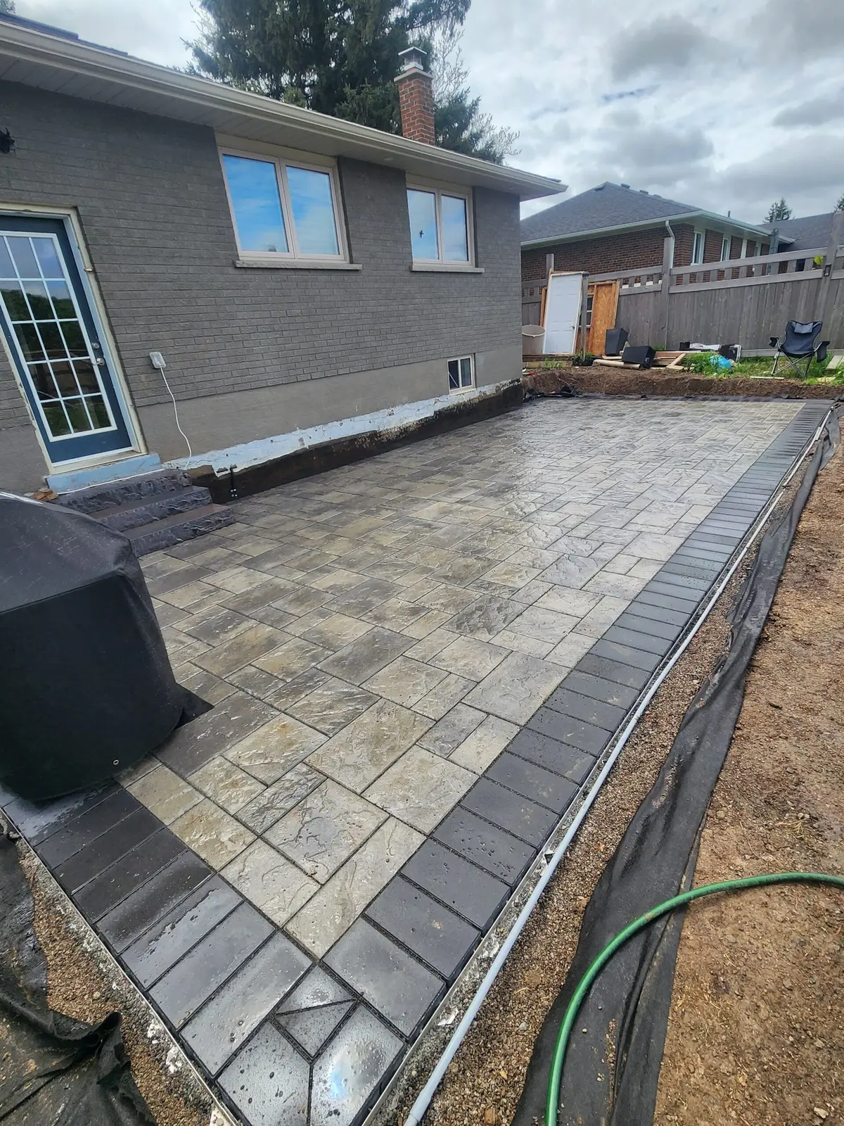 Large backyard paver patio with dark contrast border