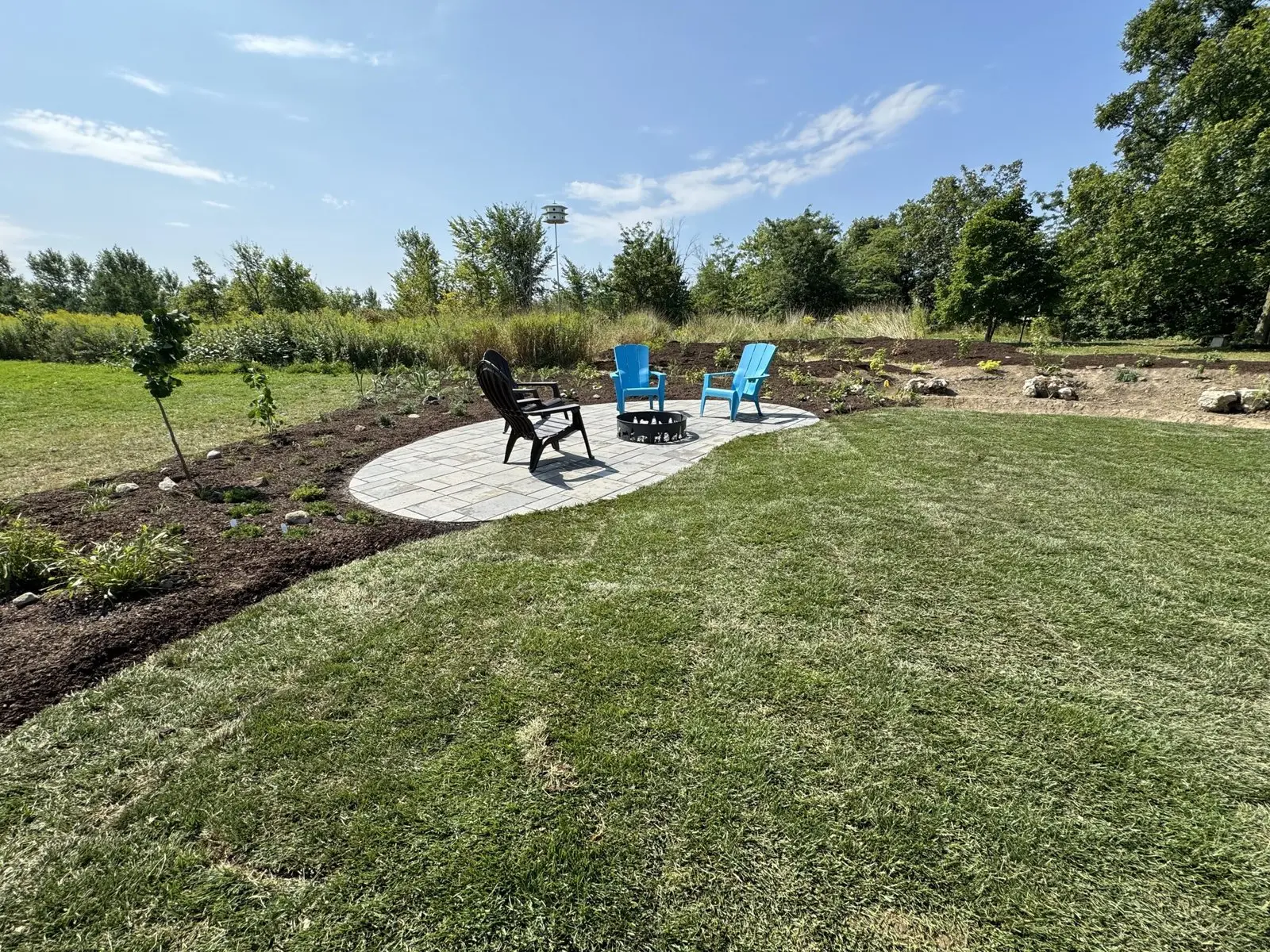 Circular paver seating area with fire pit in landscaped yard
