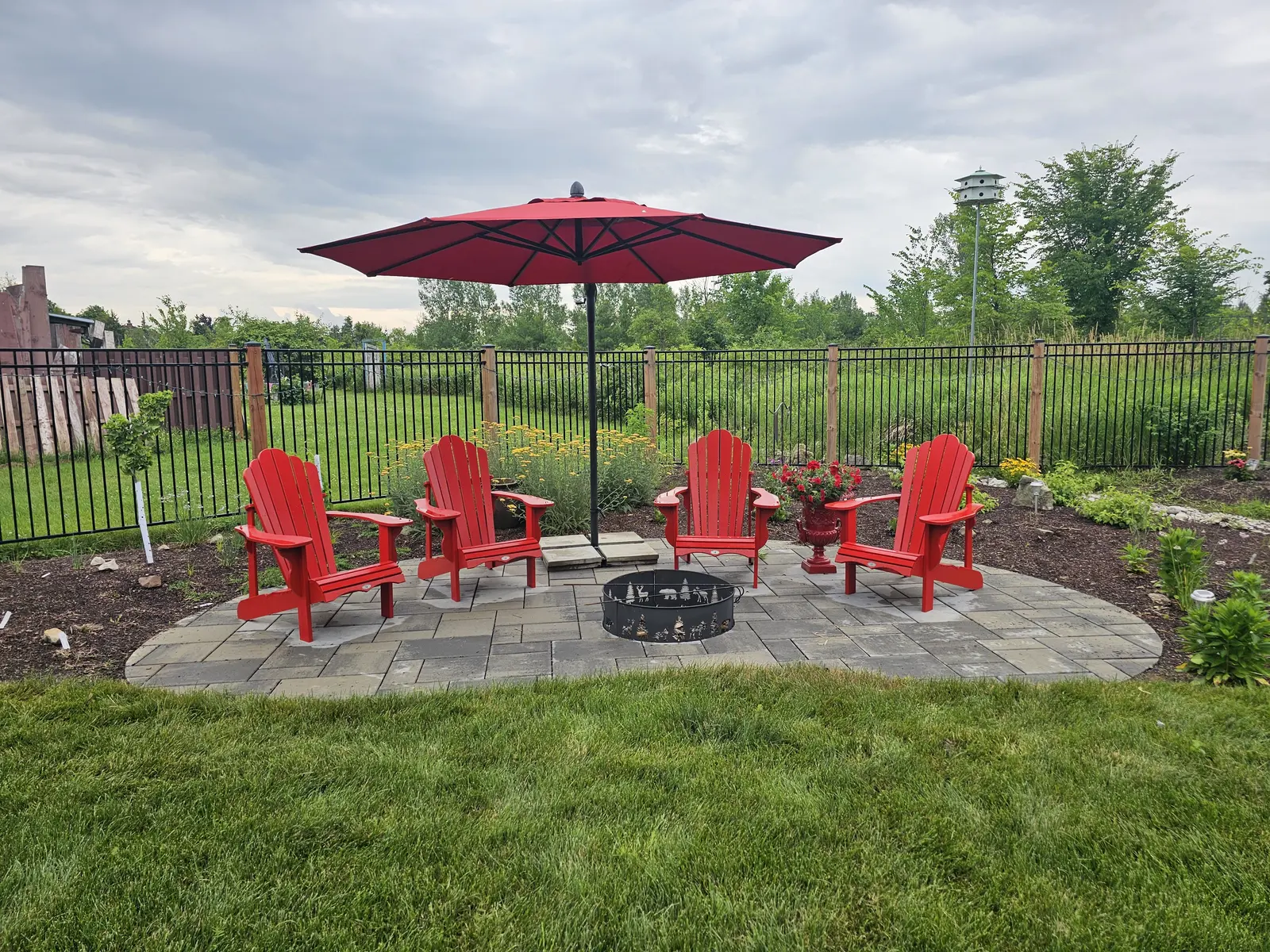 Circular paver fire pit patio with red Adirondack chairs
