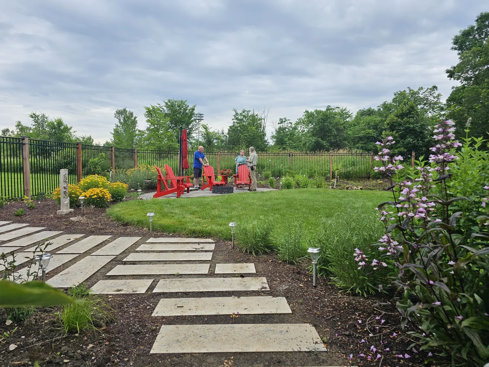 Backyard pollinator garden with Adirondack chairs & wild bergamot