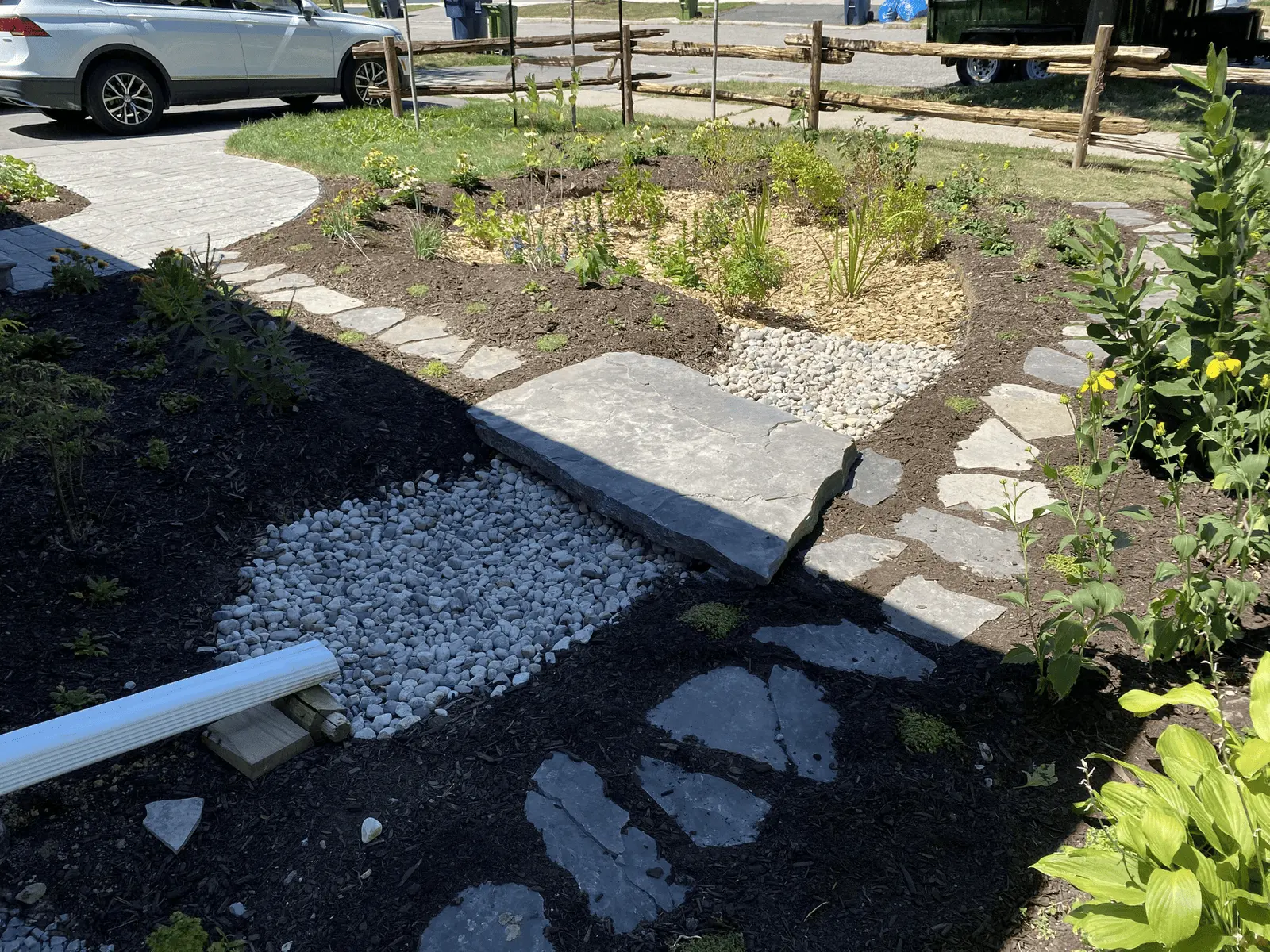 New rain garden with gravel drainage, flagstone path & split-rail fence