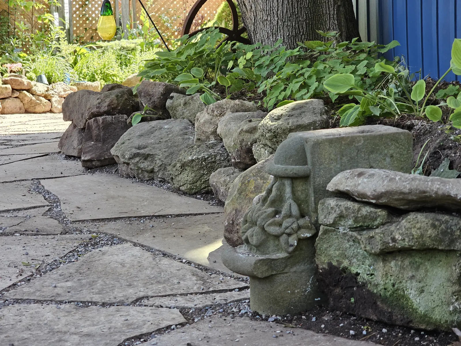 Natural mossy rock border along flagstone pathway with hostas