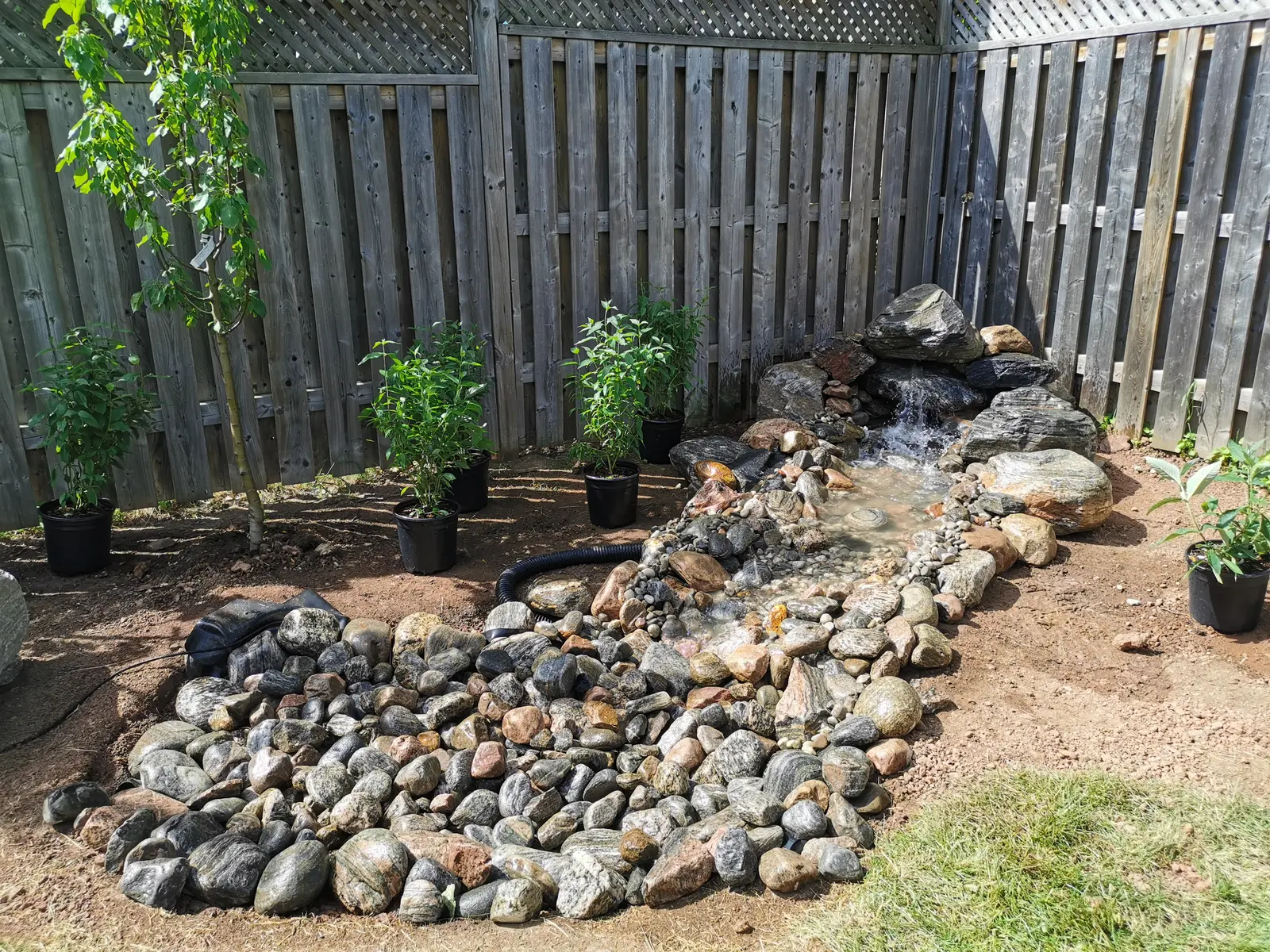 Pondless waterfall with river rock & boulders along fence