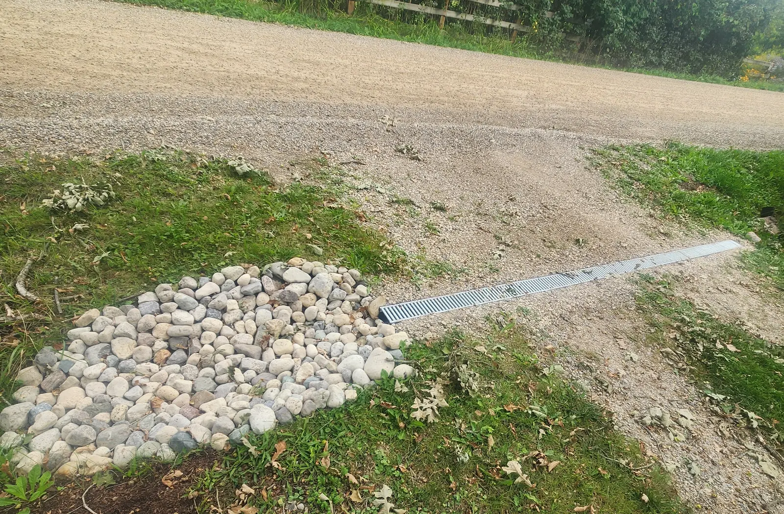 Channel drain & river rock catchment at gravel driveway edge